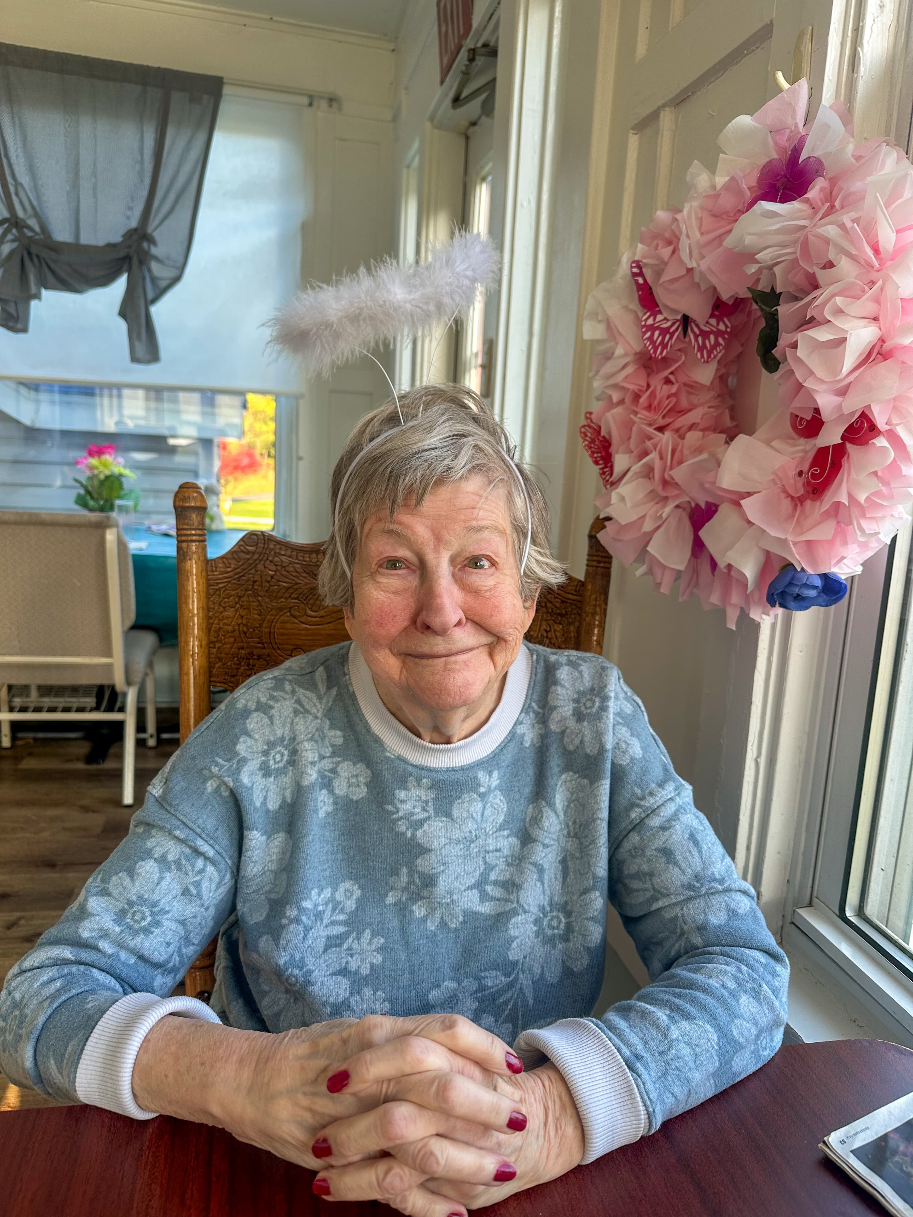 A smiling Pine View resident in a blue sweater, seated by a sunny window